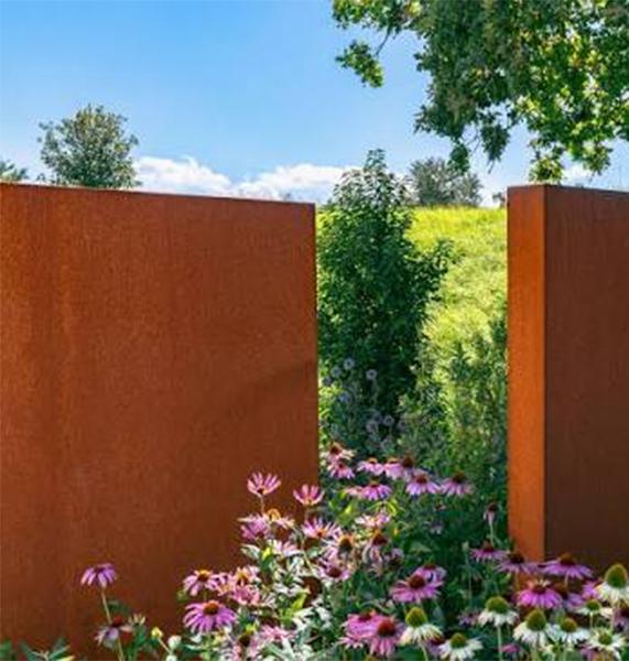 Éléments paysagers en acier Corten intégrés dans un jardin fleuri