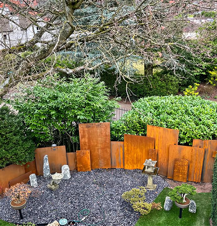 Plaques verticales en acier Corten intégrées à un jardin paysager