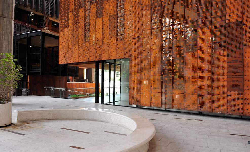 Grande enveloppe perforée en acier Corten dans un espace hospitality contemporain