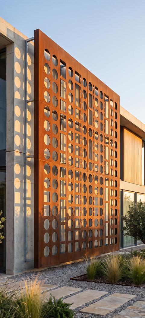 Panneau claustra en acier Corten fixé sur une façade en béton